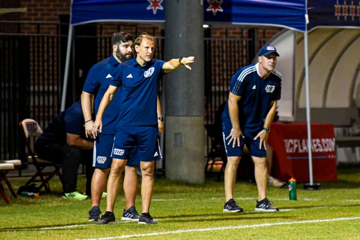 The University of Illinois-Chicago associate head coaches for men's soccer, Minos Vlamakis (back) and Aleksey Korol (front) stand on the sidelines with head coach Sean Phillips (right)